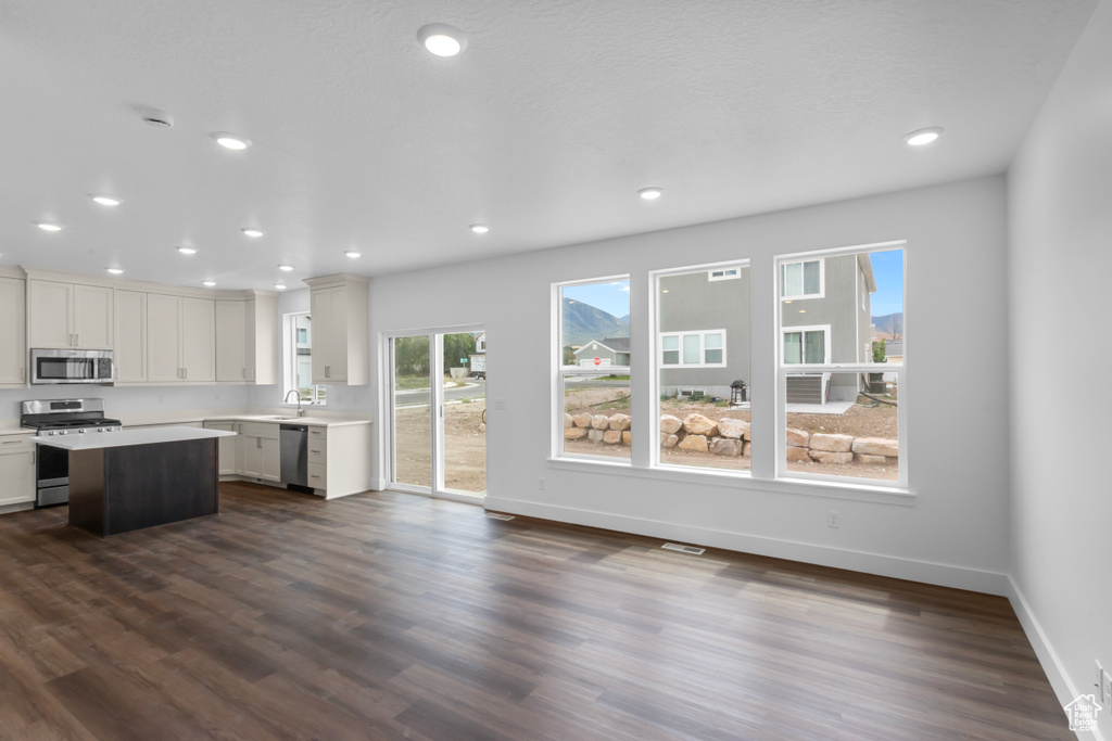 Kitchen featuring appliances with stainless steel finishes, dark wood-style floors, light countertops, a center island, and recessed lighting
