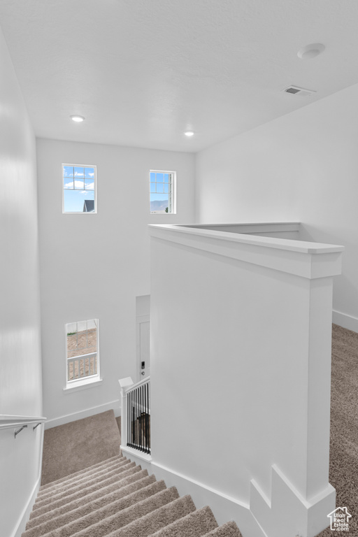 Staircase with carpet floors, plenty of natural light, and recessed lighting
