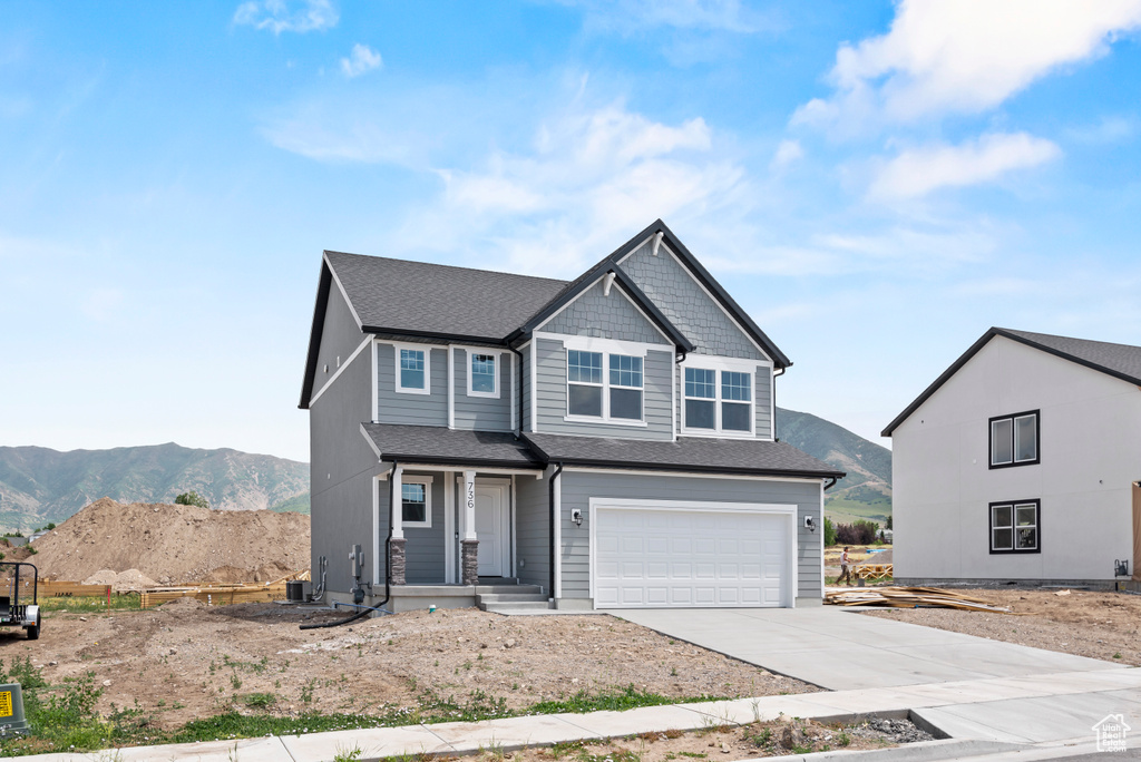 Craftsman-style home featuring an attached garage, a mountain view, driveway, a shingled roof, and covered porch