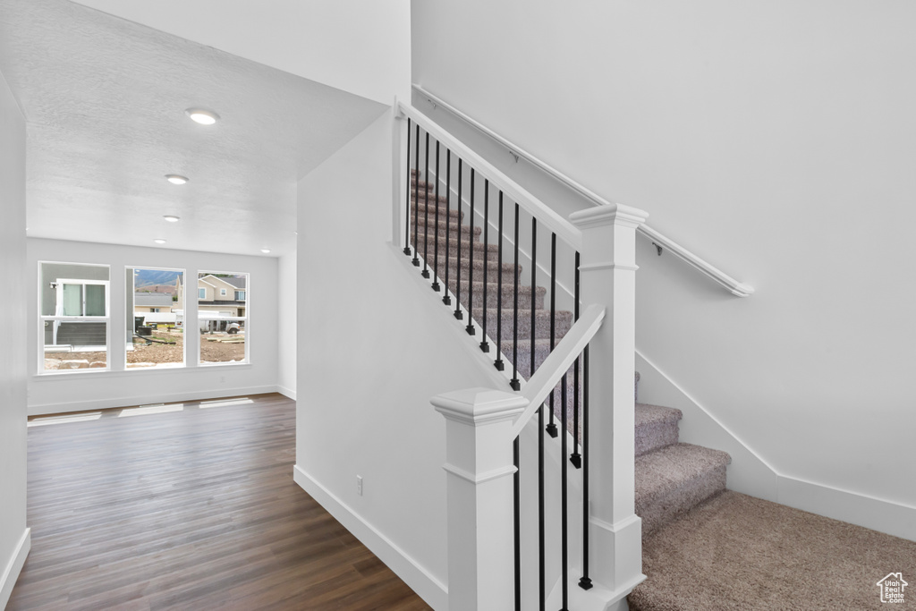 Stairway featuring wood finished floors and recessed lighting