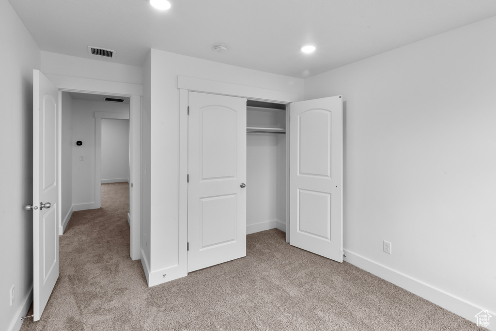 Unfurnished bedroom featuring light colored carpet, recessed lighting, and a closet