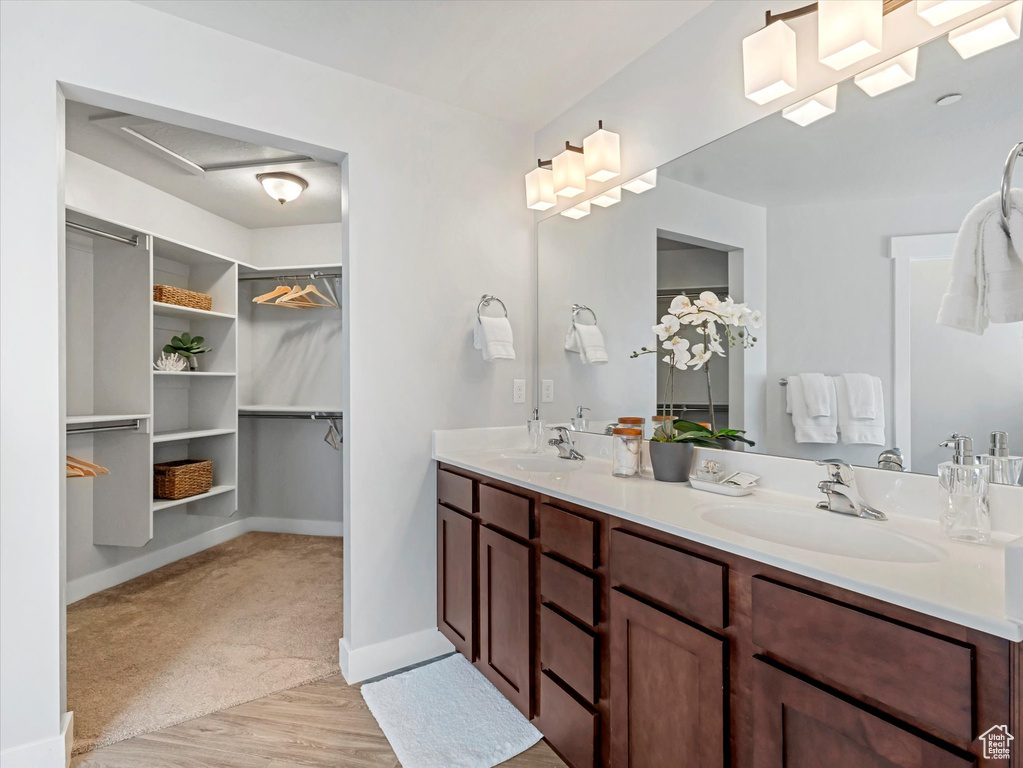 Full bath featuring double vanity, wood finished floors, and a walk in closet