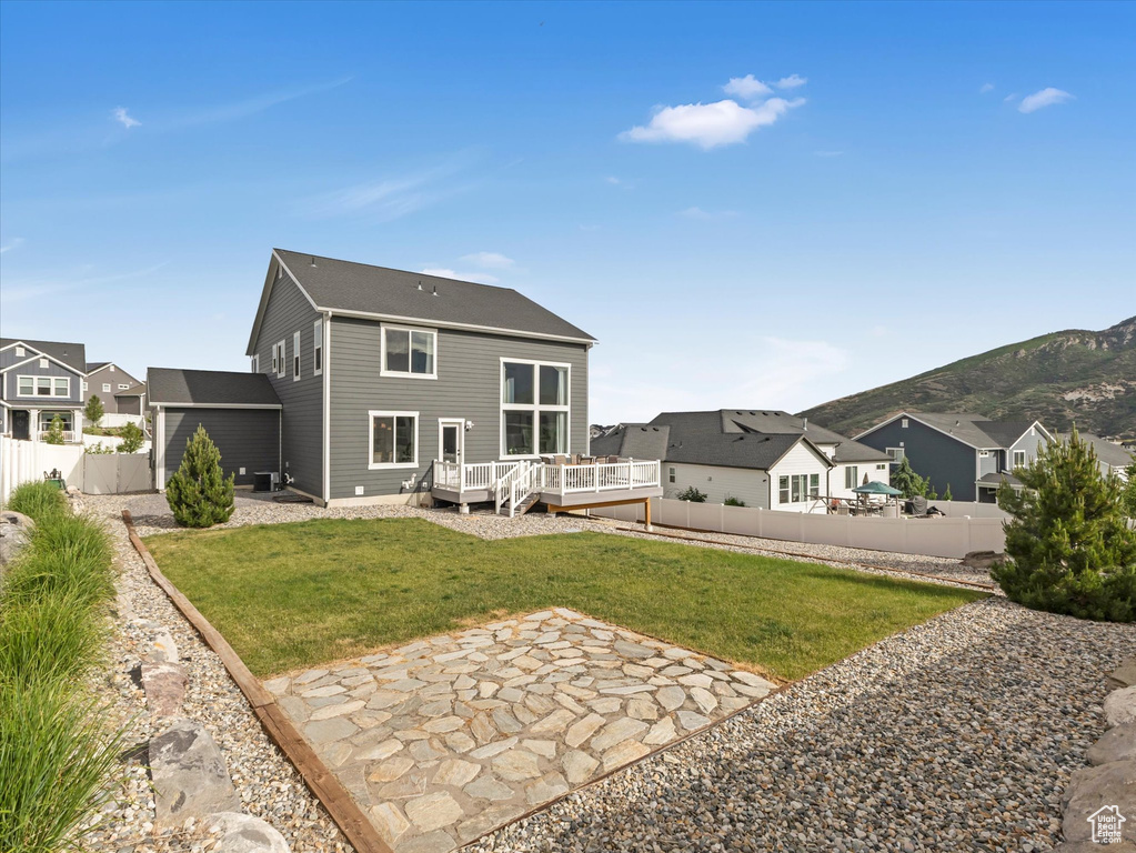 Back of property with a fenced backyard, a deck with mountain view, a patio area, and a residential view