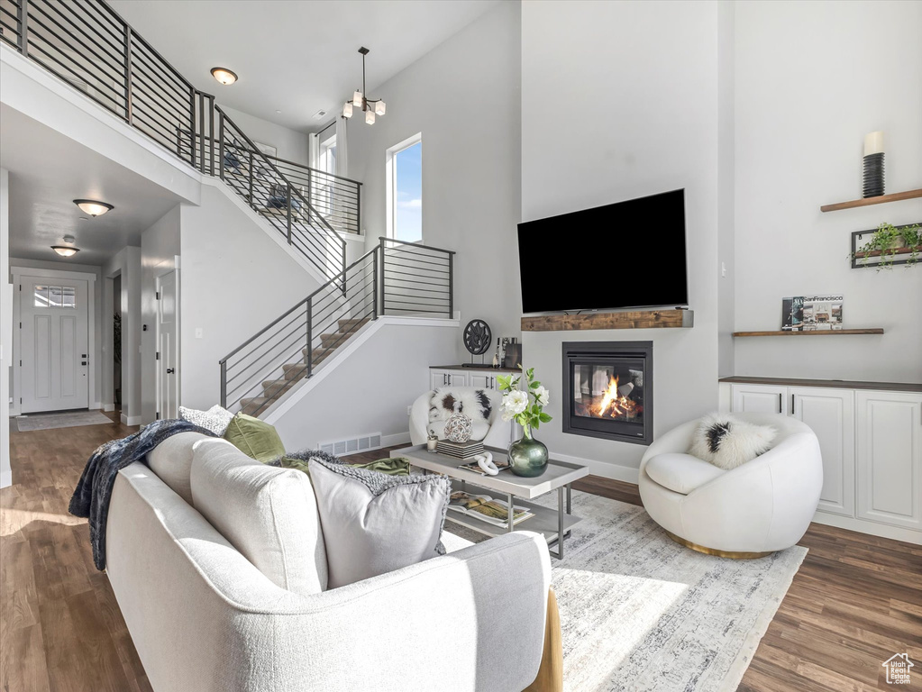 Living area with a high ceiling, wood finished floors, stairway, and a glass covered fireplace