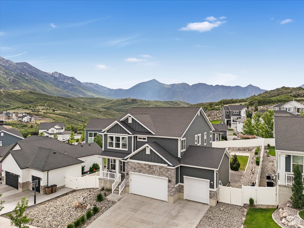 View of front of property featuring board and batten siding, stone siding, a residential view, a mountain view, and concrete driveway