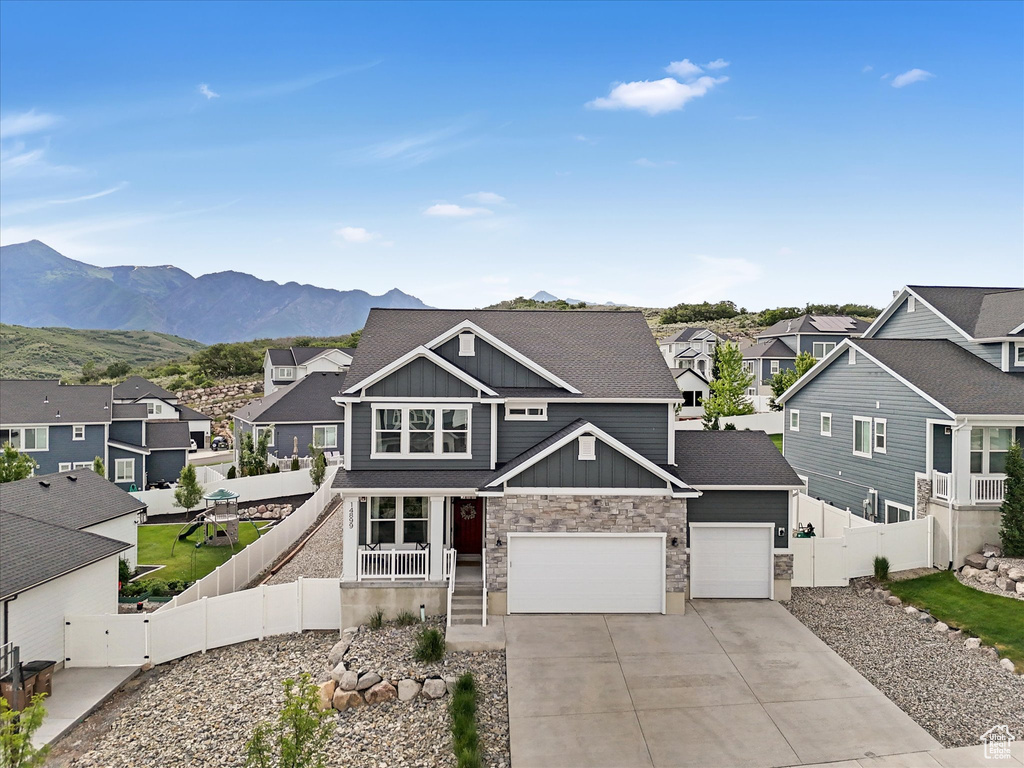 View of front of property with board and batten siding, a residential view, concrete driveway, stone siding, and a garage