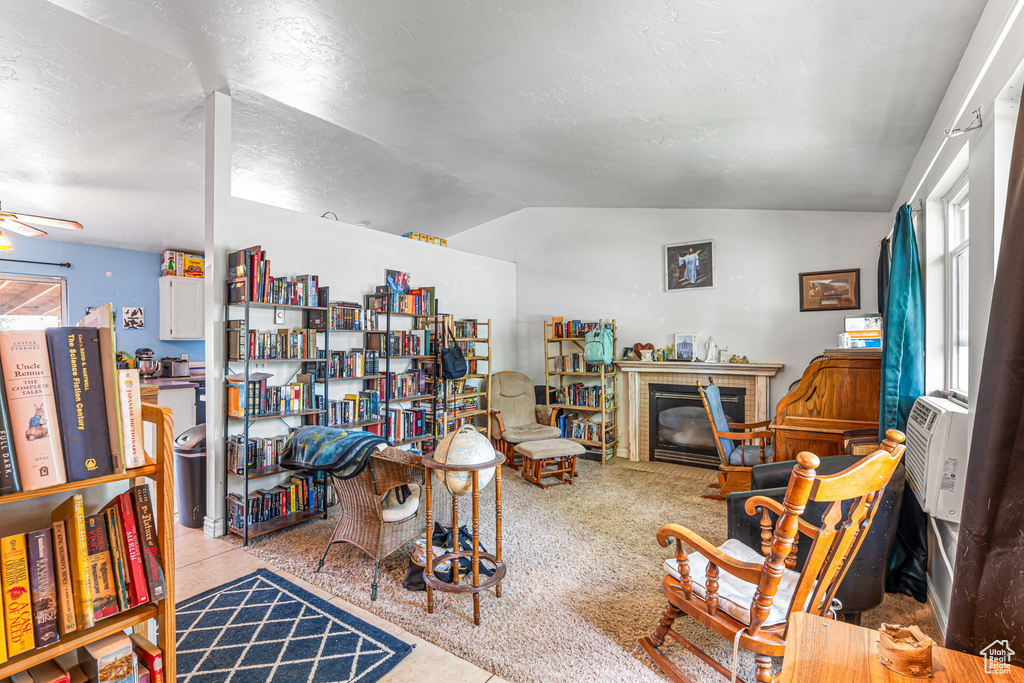Living room with lofted ceiling, a brick fireplace, ceiling fan, and a textured ceiling
