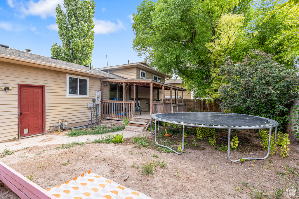 View of yard featuring a trampoline and a wooden deck