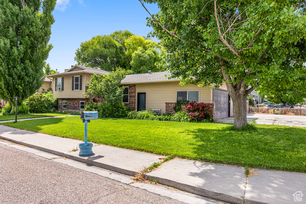 View of front of home featuring an attached garage, a front lawn, and brick siding