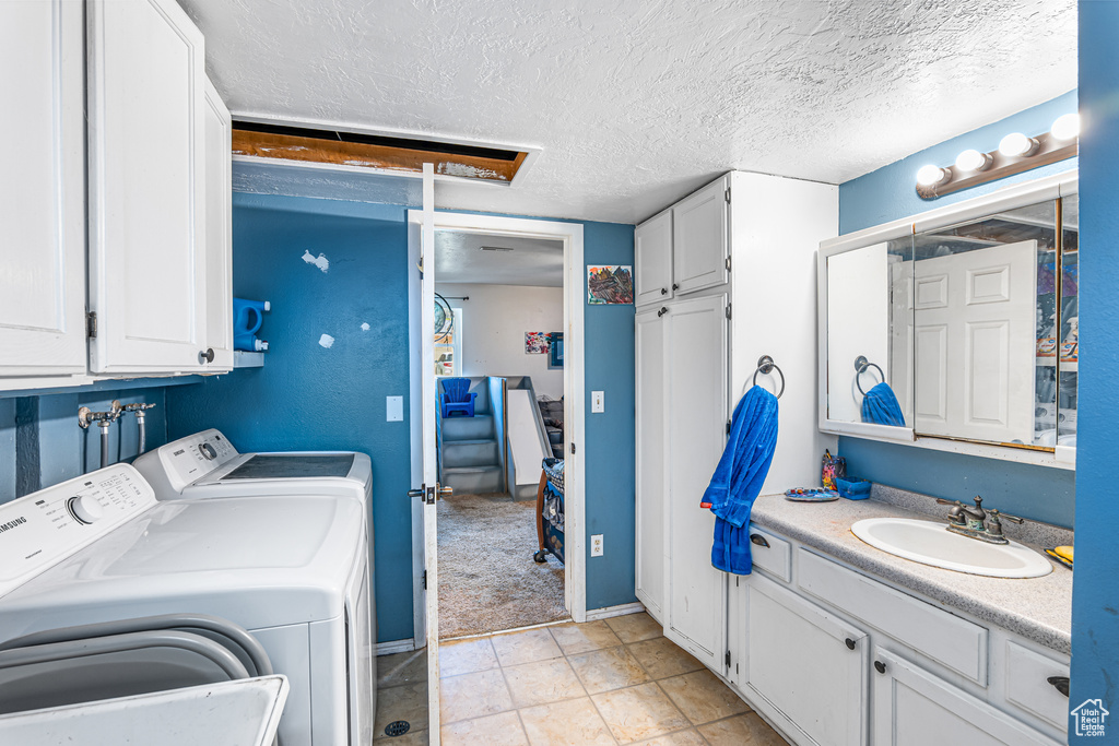 Laundry room featuring washer and clothes dryer, a textured ceiling, and cabinet space