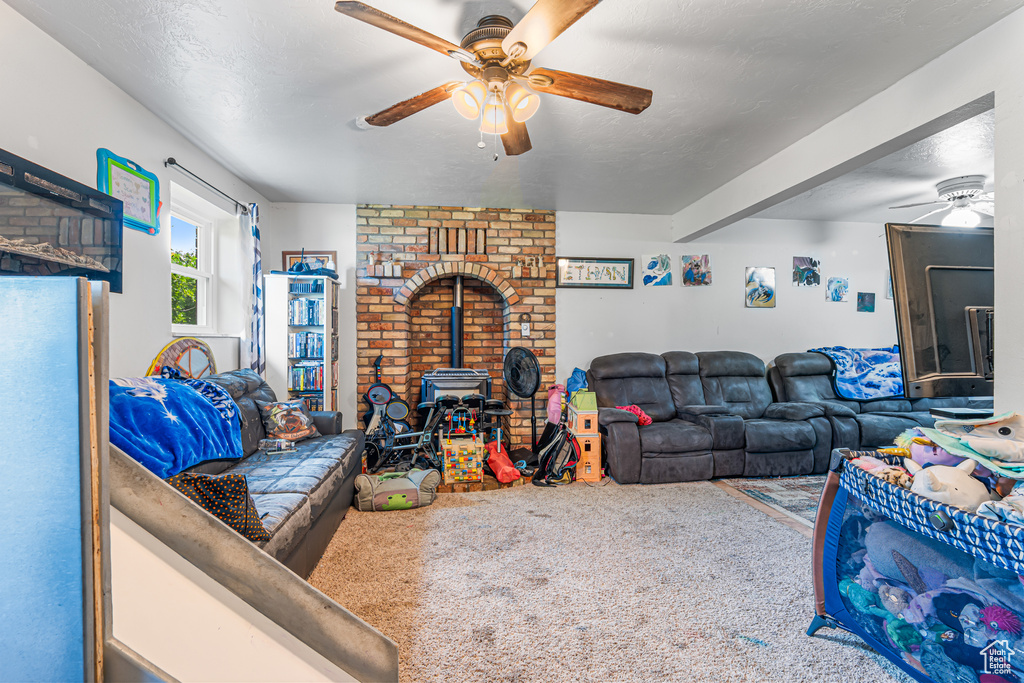 Carpeted living room featuring a ceiling fan and a wood stove