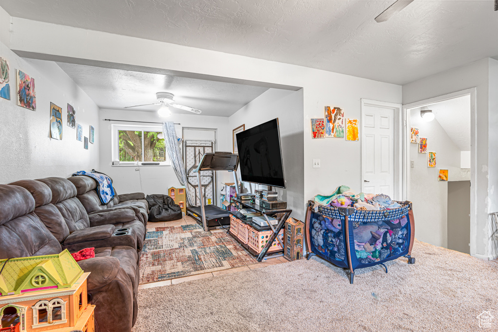 Carpeted living area with a ceiling fan and a textured ceiling