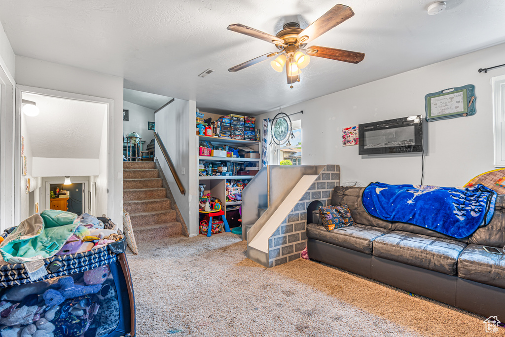Living room featuring ceiling fan, carpet floors, and stairs