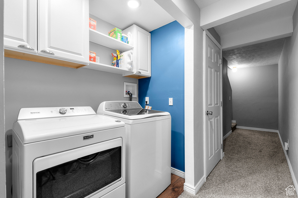Laundry room featuring washing machine and dryer, cabinet space, and carpet floors