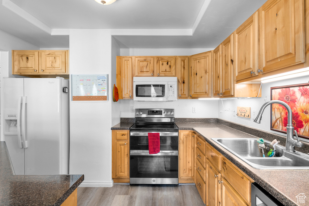 Kitchen featuring white appliances, wood finished floors, and dark countertops