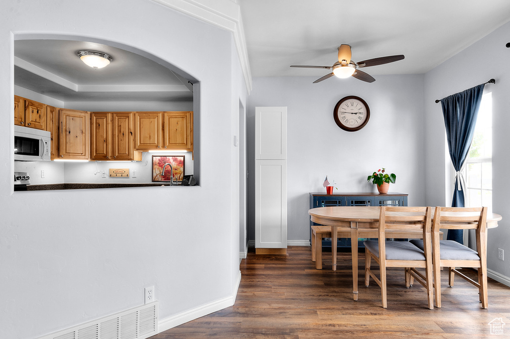 Dining space with ceiling fan, arched walkways, and wood finished floors