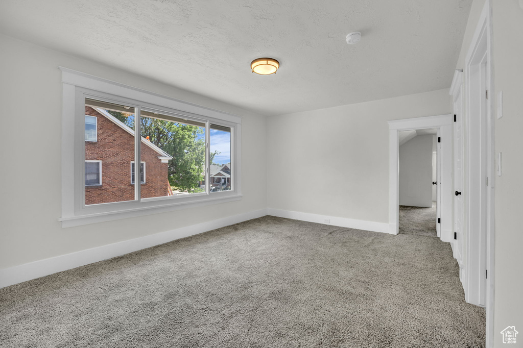 Empty room with carpet floors and a smoke detector