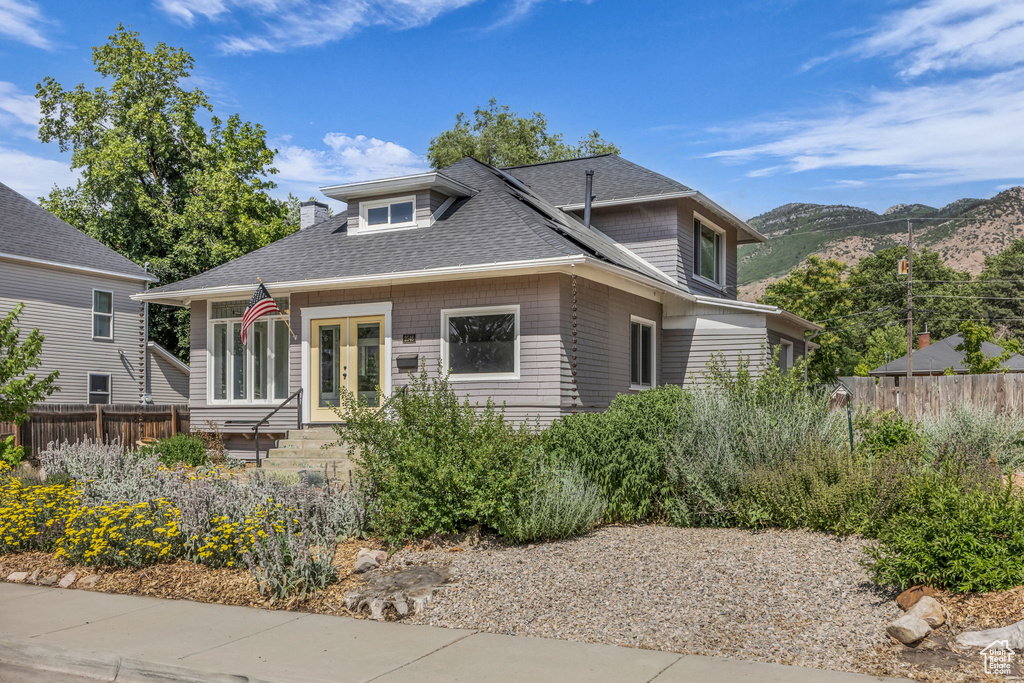 View of front of property with a mountain view, a shingled roof, and french doors