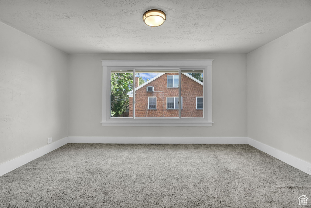 Carpeted empty room featuring baseboards and a textured ceiling