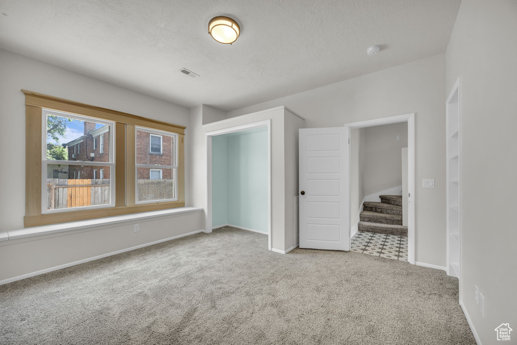 Spare room with carpet floors, a textured ceiling, stairway, and a smoke detector