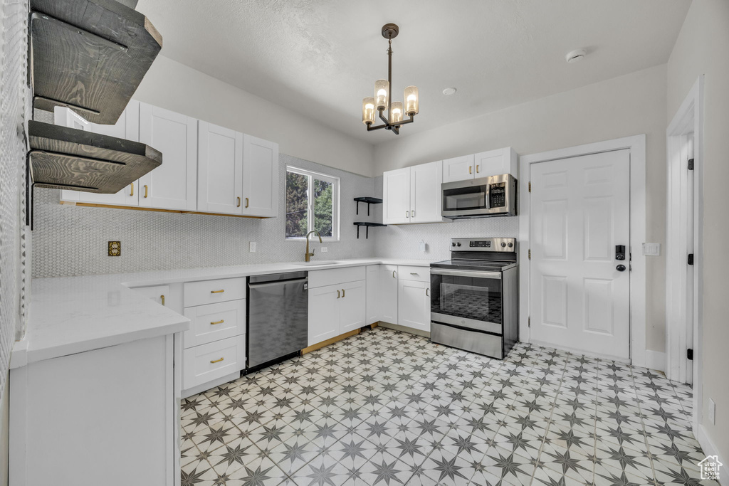 Kitchen with stainless steel appliances, light flooring, light countertops, and white cabinets