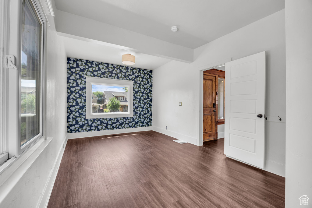 Spare room featuring dark wood-style floors, wallpapered walls, and a smoke detector