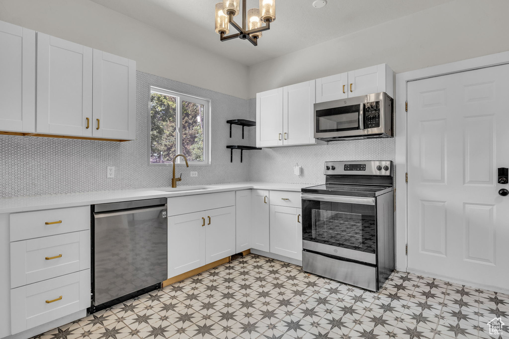 Kitchen featuring stainless steel appliances, light floors, a chandelier, and open shelves