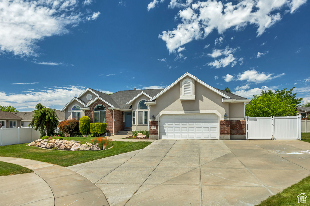 Single story home featuring brick siding, concrete driveway, a gate, and stucco siding
