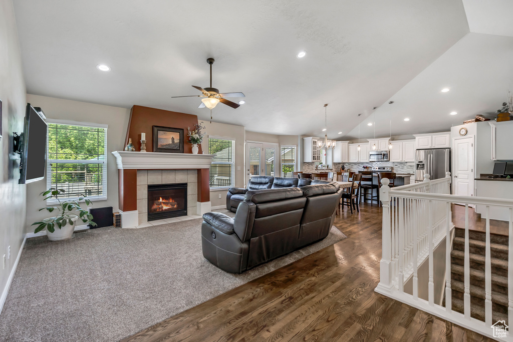 Living area featuring a fireplace, plenty of natural light, vaulted ceiling, a ceiling fan, and dark wood-type flooring