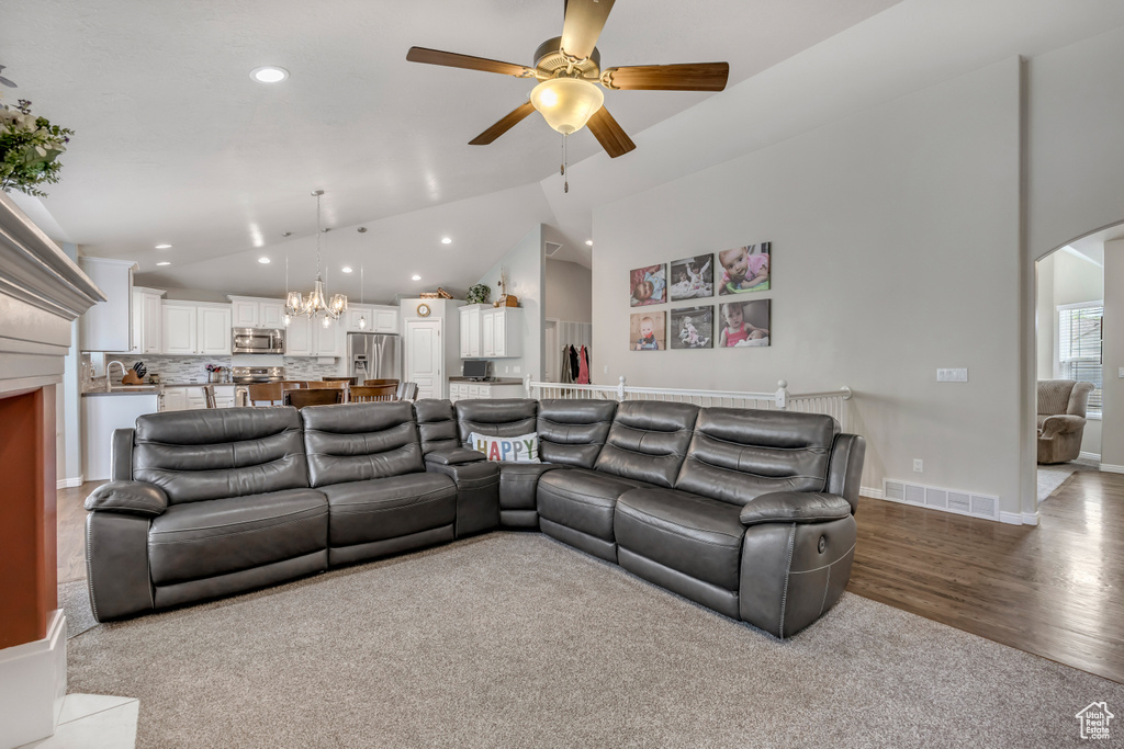 Carpeted living area with ceiling fan, arched walkways, high vaulted ceiling, recessed lighting, and a chandelier