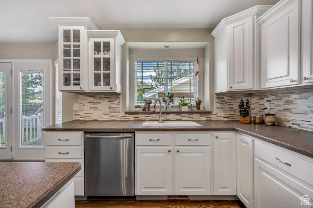 Kitchen with dishwasher, dark countertops, white cabinets, and glass insert cabinets