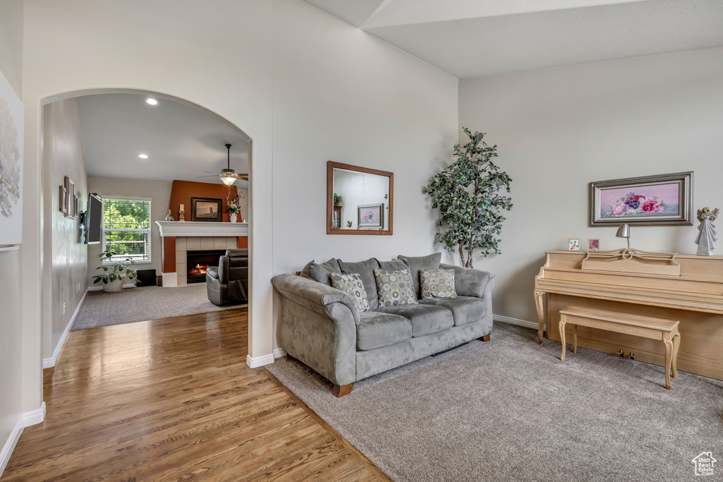 Living area featuring a ceiling fan, arched walkways, wood finished floors, a fireplace, and recessed lighting