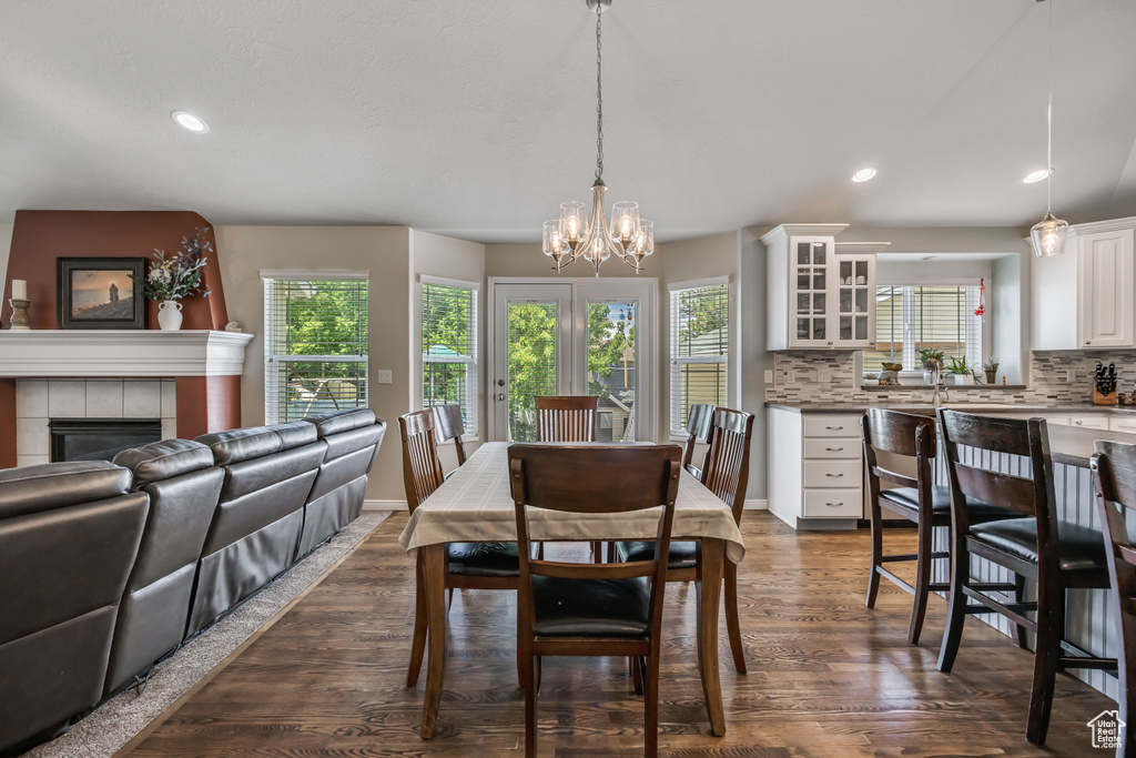 Dining area with dark wood-type flooring, a chandelier, a fireplace, and recessed lighting