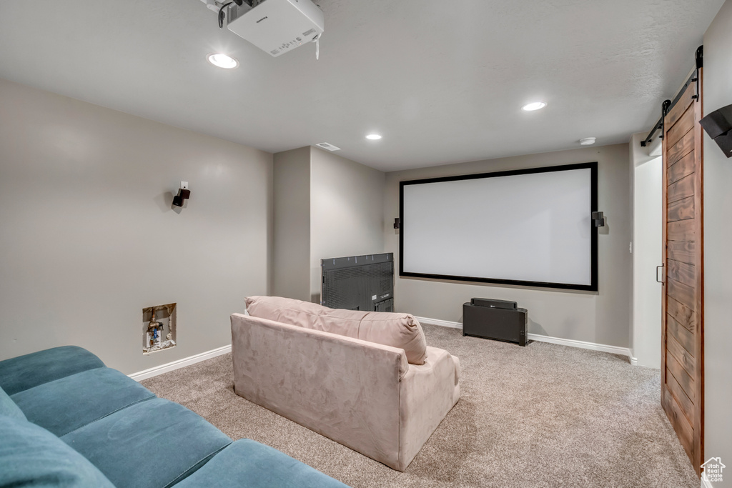 Carpeted home theater room with a barn door and recessed lighting