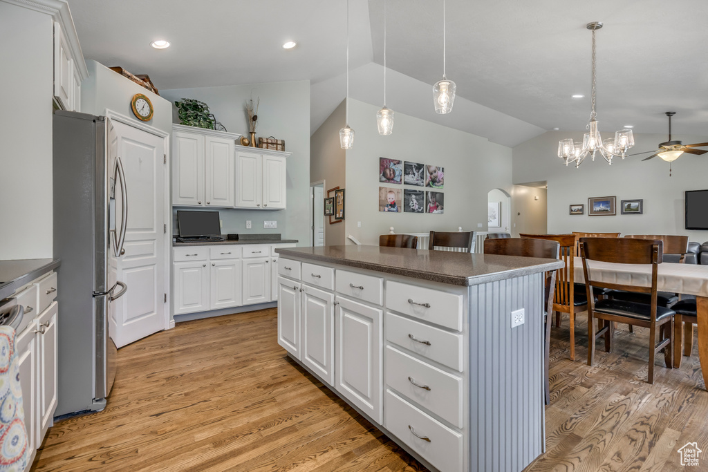 Kitchen featuring vaulted ceiling, freestanding refrigerator, dark countertops, a center island, and light wood-type flooring