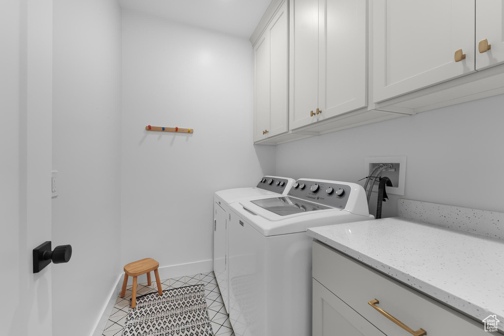 Washroom featuring cabinet space, washer and clothes dryer, and light tile patterned floors