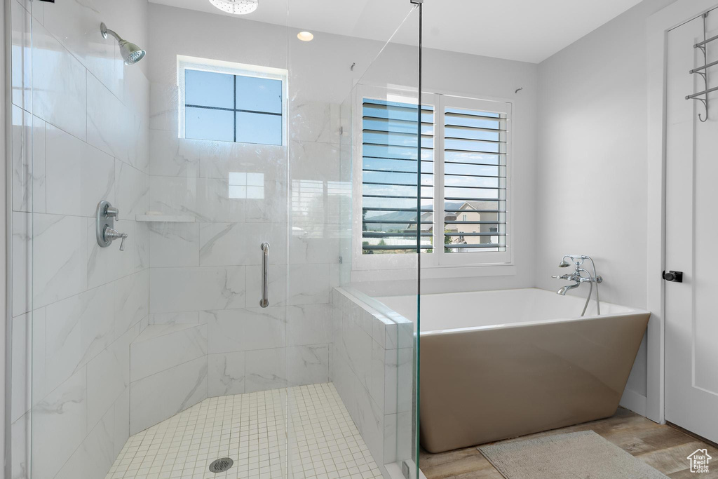 Full bathroom featuring healthy amount of natural light, a stall shower, a freestanding tub, and wood finished floors