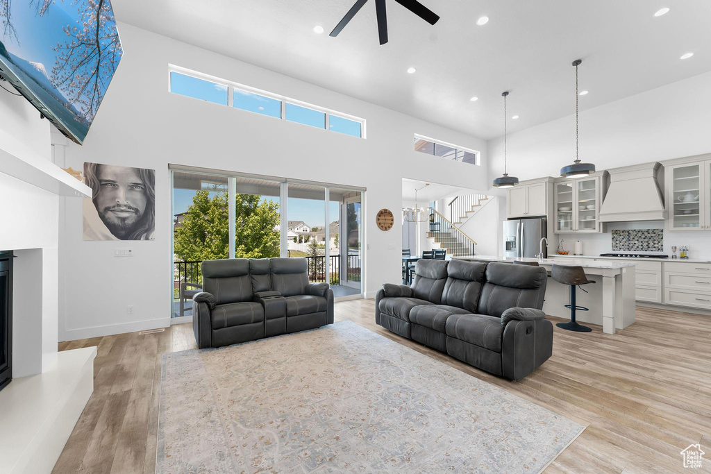 Living room featuring a ceiling fan, stairs, recessed lighting, a high ceiling, and healthy amount of natural light