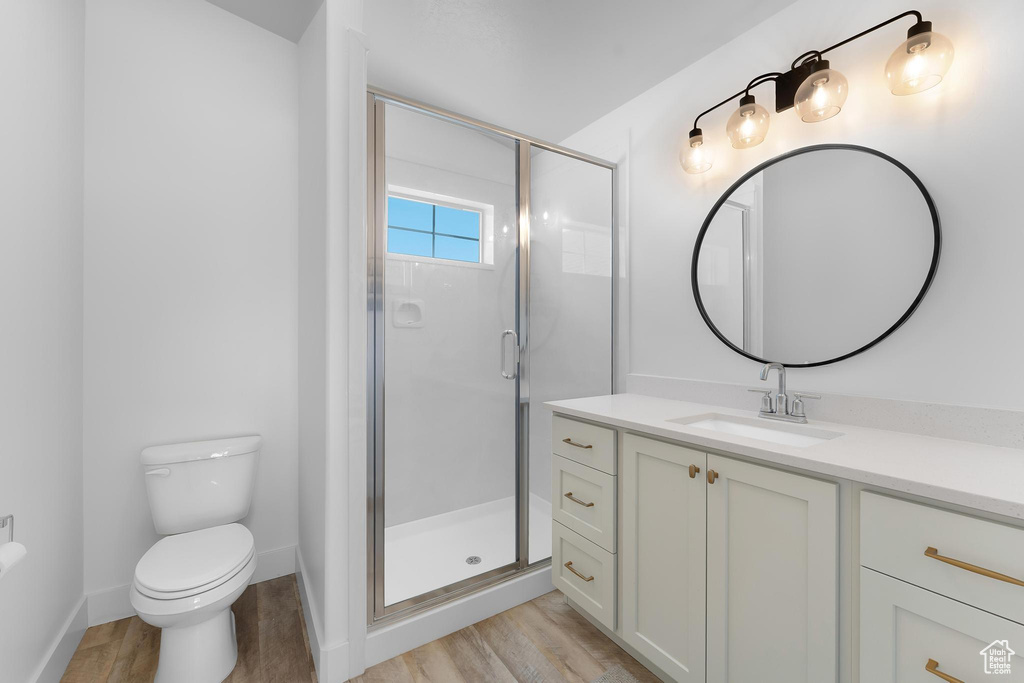 Full bath featuring vanity, wood finished floors, and a stall shower