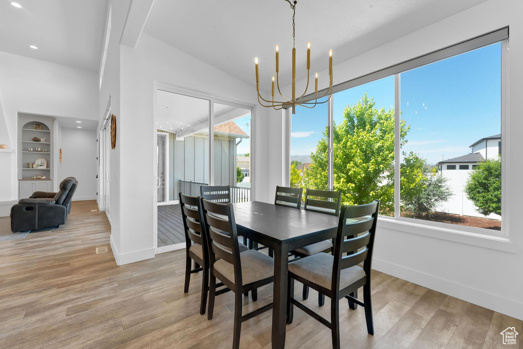 Dining area with light wood-type flooring, a chandelier, recessed lighting, and built in shelves