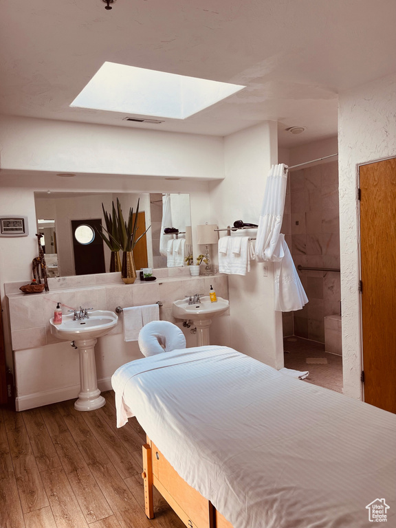 Bedroom with a skylight and wood finished floors