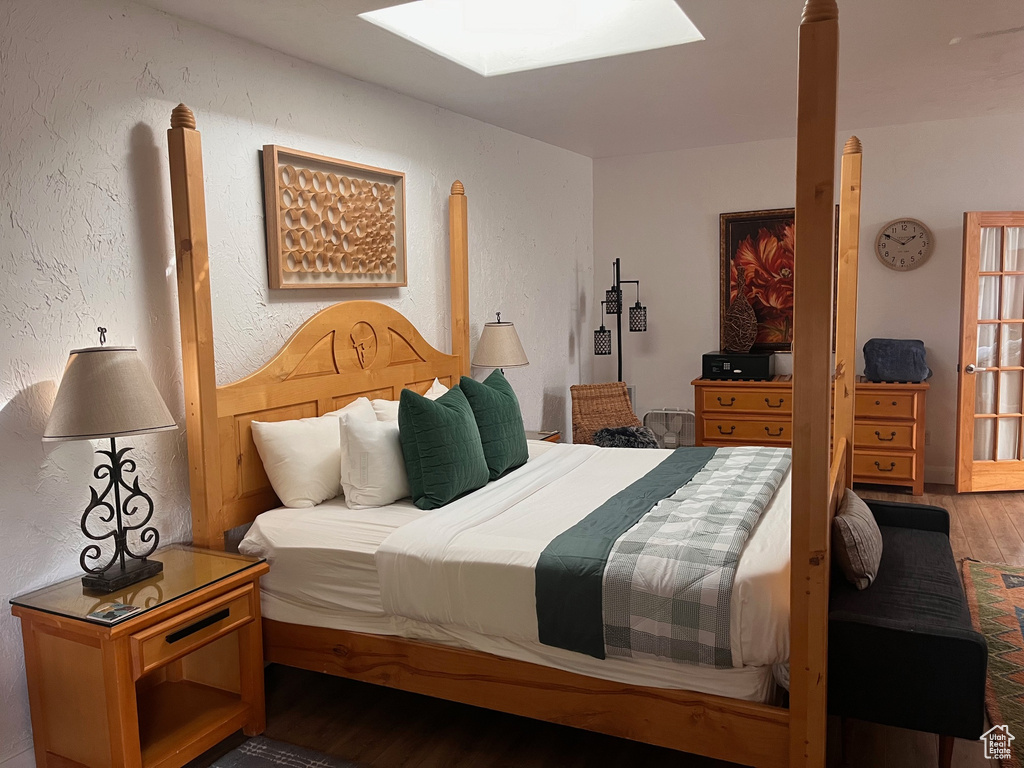 Bedroom featuring wood finished floors, a skylight, and a textured wall