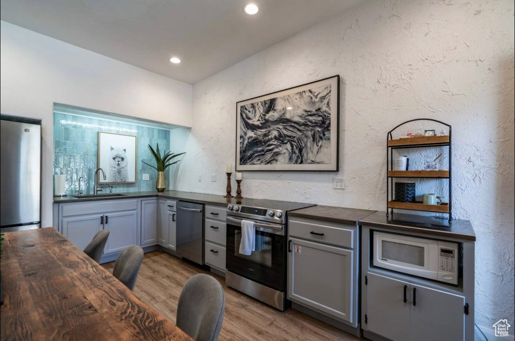 Home office with a sink, wood finished floors, a textured wall, and recessed lighting