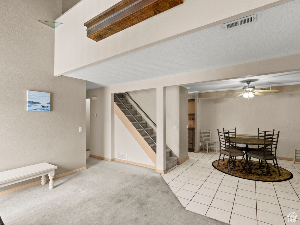 Dining room featuring stairway, a ceiling fan, light colored carpet, and light tile patterned flooring