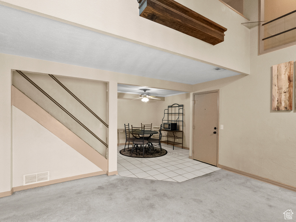 Entrance foyer with light carpet, stairs, and ceiling fan