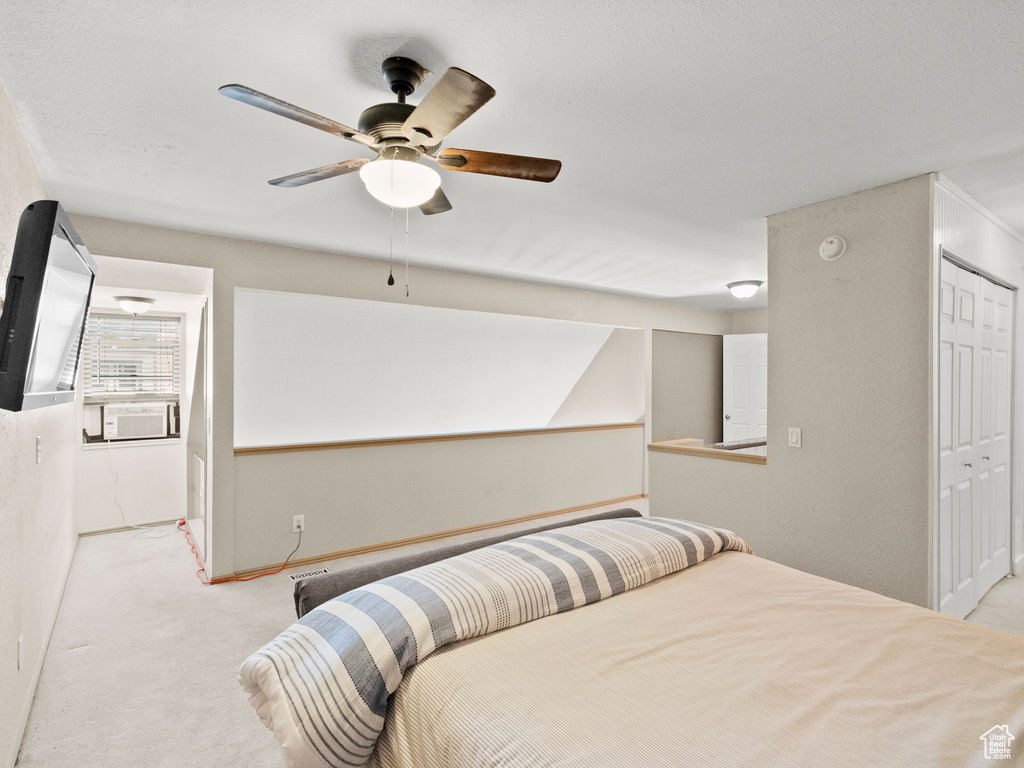 Carpeted bedroom with cooling unit, a closet, and a ceiling fan