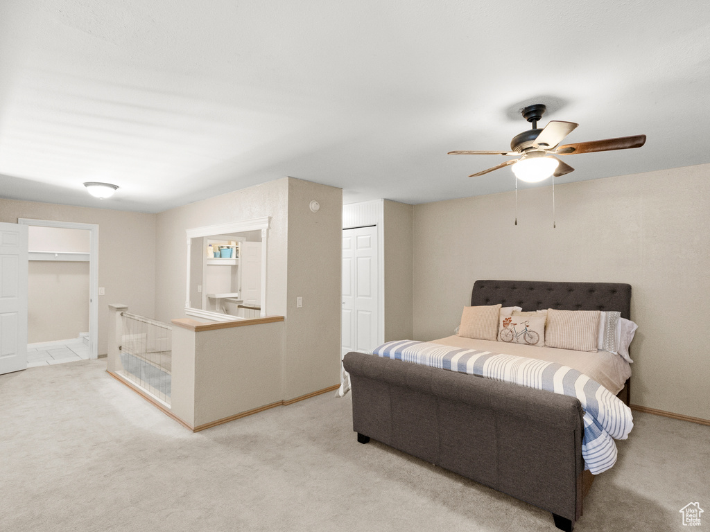 Bedroom featuring light colored carpet, a ceiling fan, and a closet