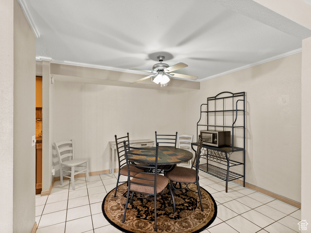 Dining room featuring crown molding, light tile patterned floors, and a ceiling fan