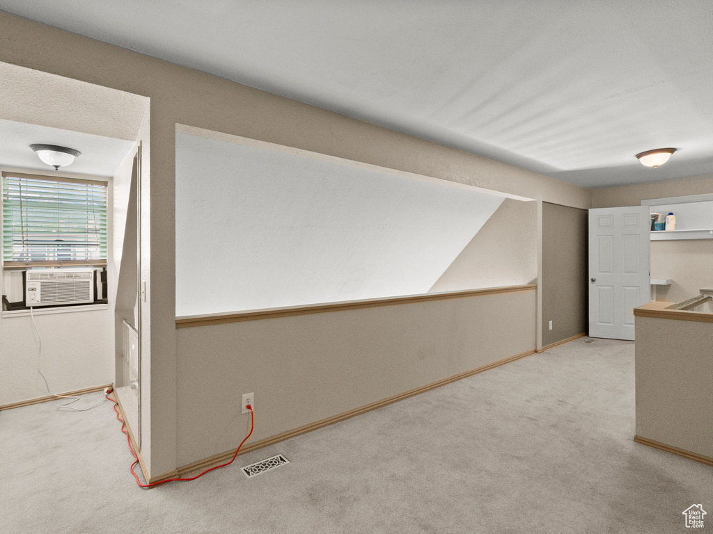 Hallway with carpet floors, cooling unit, and vaulted ceiling