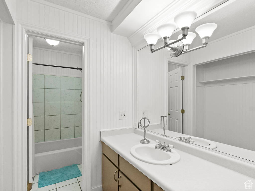 Full bath with tile patterned floors, vanity, ornamental molding, a chandelier, and shower / washtub combination